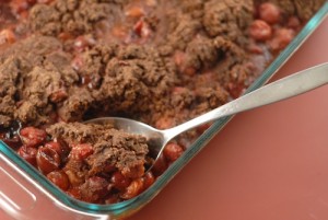 cherry chocolate cobbler shown in a baking dish with serving spoon